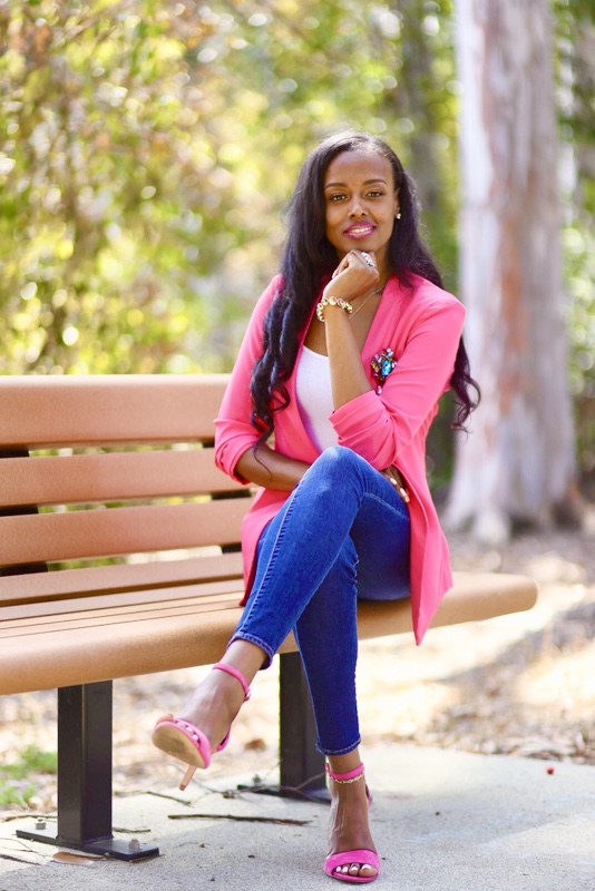 A woman in a pink blazer sitting on a park bench smiling. A woman in a pink blazer sitting on a park bench smiling.