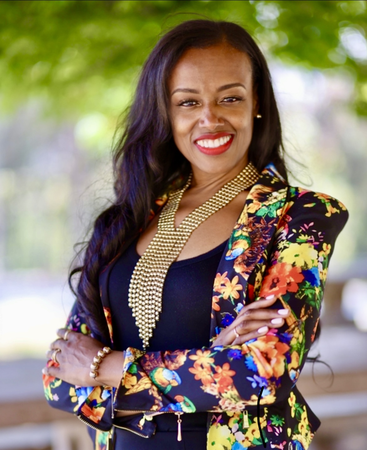 Confident woman smiling, wearing a colorful floral blazer outdoors. Confident woman smiling, wearing a colorful floral blazer outdoors.