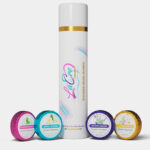 A tall white bottle with gold accents surrounded by four colorful small containers.