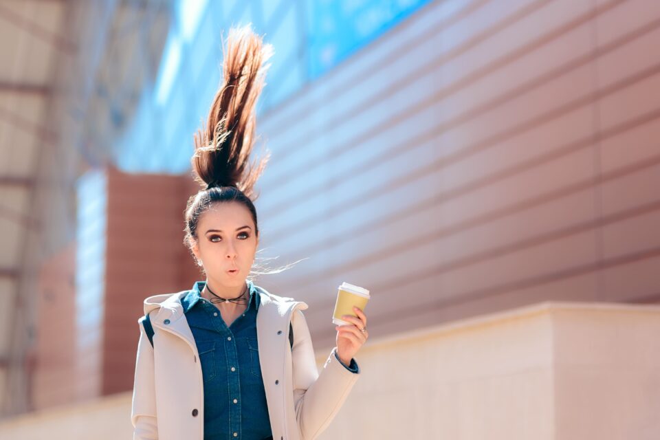 Woman with hair flying upward holding an ice cream cone outdoors.