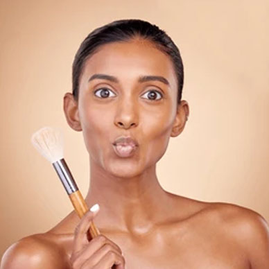 Woman applying makeup with a brush, puckering her lips.