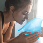 Woman inhaling steam from a facial steamer for skincare.