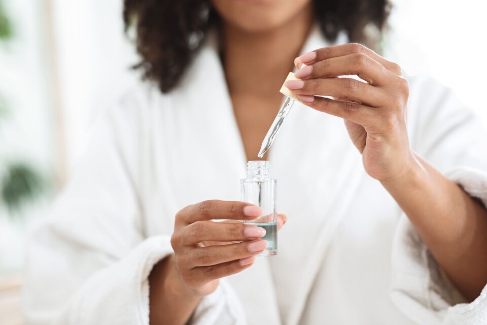 Person using a dropper to add liquid into a clear glass of water.