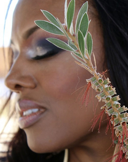 Close-up of a woman with artistic eye makeup and a plant near her face. Close-up of a woman with artistic eye makeup and a plant near her face.
